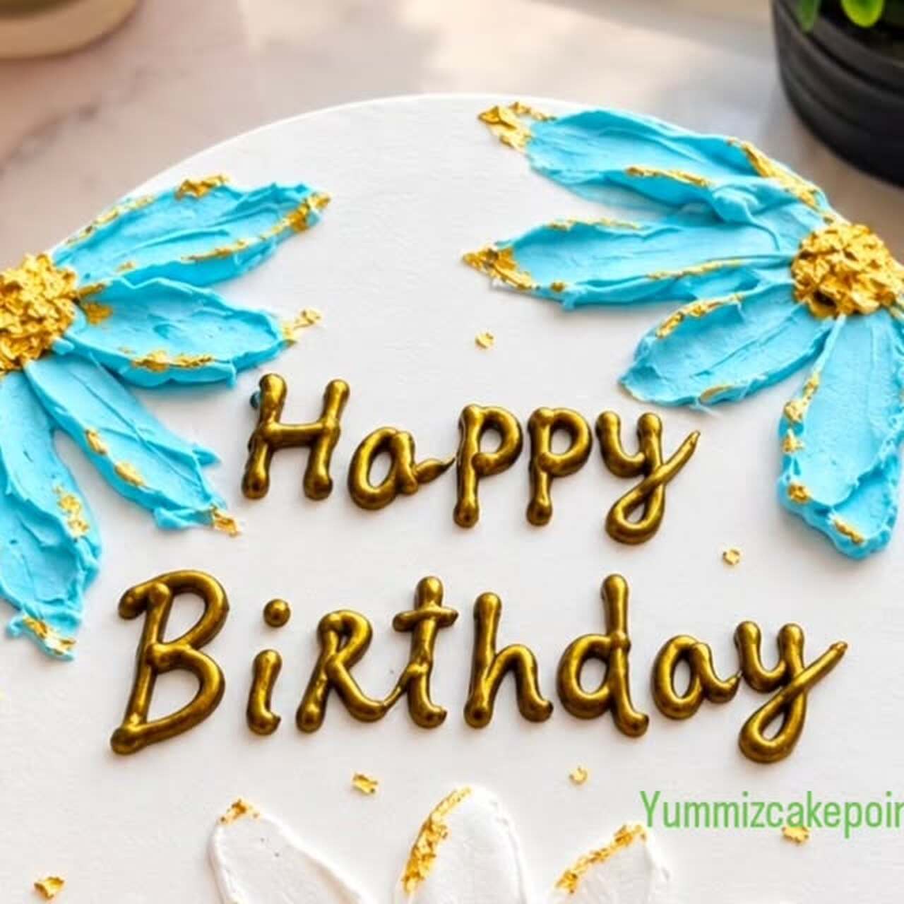 Butterscotch birthday cake with blue and white palette-knife flowers